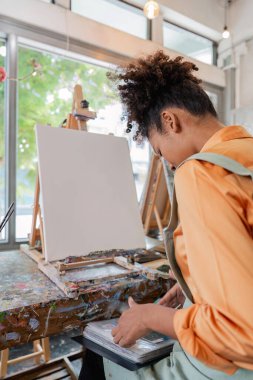 Güzel Afrikalı Amerikalı kadın ressam resim stüdyosunda kendine güveniyor..