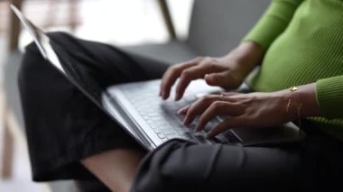 Kanepede oturup dizüstü bilgisayar kullanan, dizüstü bilgisayar kullanan genç bir kadının elini kapat..