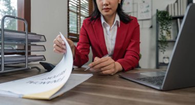 İş kadını ofis masasında otururken şirket gelirini ve giderlerini not alıyor..