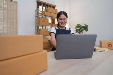 Genç iş kadını dükkanında online ekommerce alışverişi yapıyor. Genç kadın satıcı müşteriye teslim etmek için bir paket ürün hazırla. Çevrimiçi satış, ekommerce.