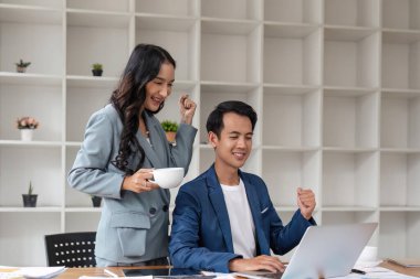 İş stratejisi başarılı. Coşkulu meslektaşlar duygusal olarak zaferi kutluyor, ofisteki bilgisayar ekranına bakıyor..