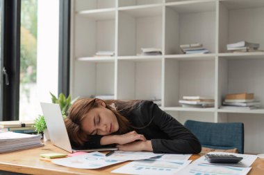 Ofiste dizüstü bilgisayarda uyuyan yorgun ve çok çalışan bir iş kadını..