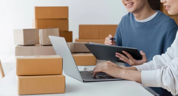 stock image Happy couple people packing parcel boxes, couple lover checking order online on laptop at home.