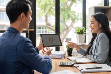 Ofiste birlikte çalışan mutlu iş adamları dizüstü bilgisayarlarını kullanarak şirketin finans ve vergilerini analiz ediyorlar..