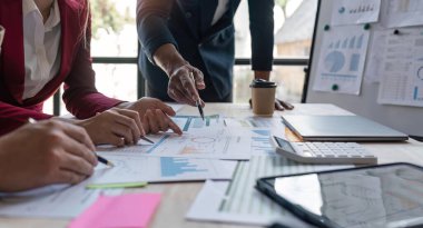 Ofisteki analist ekibi, pazarlama stratejisi için finansal veri analizini, performans ve yönetimi optimize etmek için grafik ve grafikli konsol kağıdı formatını analiz ediyor.