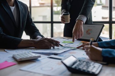 Ofisteki analist ekibi, pazarlama stratejisi için finansal veri analizini, performans ve yönetimi optimize etmek için grafik ve grafikli konsol kağıdı formatını analiz ediyor.