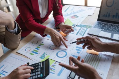 Ofisteki analist ekibi, pazarlama stratejisi için finansal veri analizini, performans ve yönetimi optimize etmek için grafik ve grafikli konsol kağıdı formatını analiz ediyor.