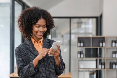 Ofisteki güzel iş kadını, mutlu ve gülümseyen iş kadını internet telefonunu kapatıyor, kadın çalışan mesajları okuyor ve ofis içi internet sayfalarını karıştırıyor..