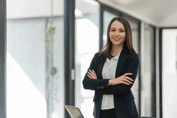 stock image Beautiful businesswoman standing with her arms wrapped around her chest in office.