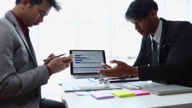 Elinde elektronik tablet bulunan iki Asyalı işadamı ve hesap makinesi şirketin iş planını hazırlıyor..