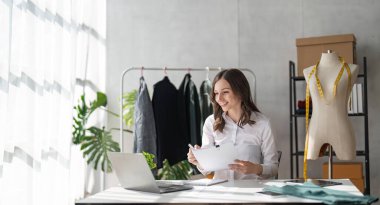 Kadın moda tasarımcısı yeni moda kıyafet koleksiyonu tasarlıyor. Moda tasarımcısı stüdyoda çalışıyor..