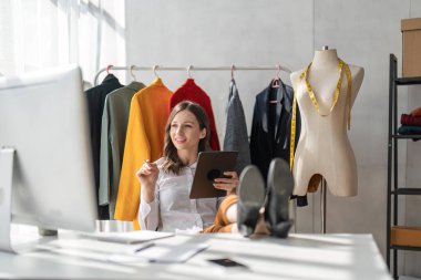 Kadın moda tasarımcısı yeni moda kıyafet koleksiyonu tasarlıyor. Moda tasarımcısı stüdyoda çalışıyor..