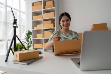 Genç iş kadını dükkanında online e-ticaret alışverişi yapıyor. Genç kadın satıcı müşteriye teslim etmek için bir paket ürün hazırla. Online satış, e-ticaret.