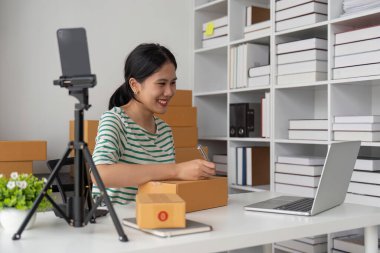 Genç iş kadını dükkanında online e-ticaret alışverişi yapıyor. Genç kadın satıcı müşteriye teslim etmek için bir paket ürün hazırla. Online satış, e-ticaret.