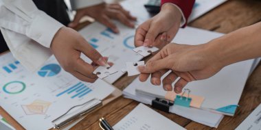 Takım çalışması ve ortaklık kavramı. Eller yapboz parçalarını ofiste birleştirir. İş adamları yapboz takımını bir araya getiriyor. Hayır kurumu, gönüllü. Birlik, takım işi.