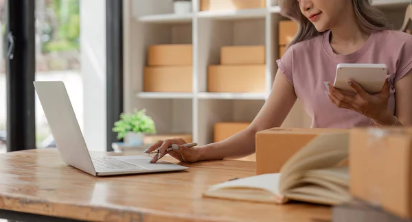 贴身女性在办公室里用笔记本电脑和产品订单计算器在线销售衣服 网上商店邮包 — 图库照片