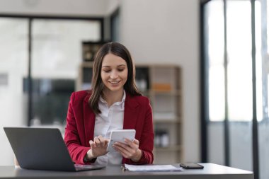 Businesswoman using a calculator to check company finances and earnings and budget. Business woman calculating monthly expenses, managing budget, papers, loan documents, invoices.