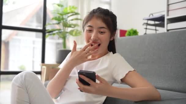 美しいアジアの女性は 携帯電話でソーシャルメディアを再生良いニュースを受信驚いた スマートフォンを持った興奮した女の子がメッセージを送る — ストック動画