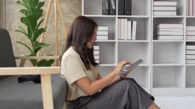 Mutlu kadın evde tablet kullanarak mesajlaşmayı gevşet.