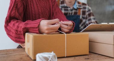 İşyerinde bilgisayarla çalışan birkaç küçük işletme sahibi. Birkaç iş adamı ürün siparişini kontrol ediyor. Müşteriye teslimat için mal paketliyorum. Çevrimiçi satış. E-ticaret. Nakliye kavramı.