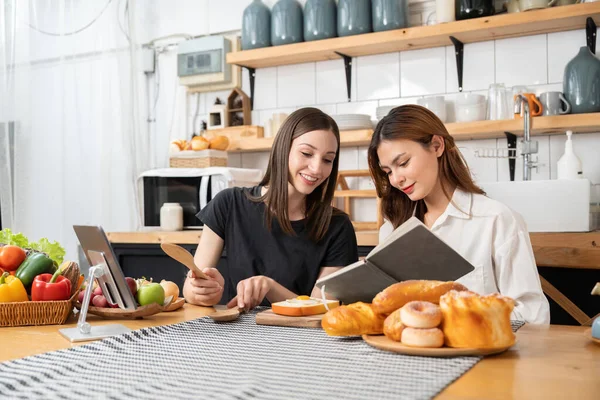 Feliz Duas Jovens Mulheres Trabalhando Cozinhar Enquanto Ela Está Lendo — Fotografia de Stock