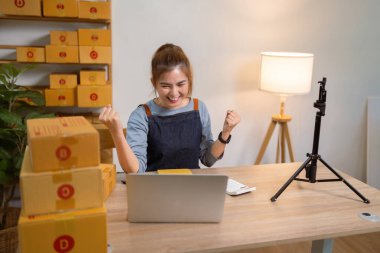 Mağazasında online e-ticaret alışverişinde çalışan genç bir kadın satışlardan memnun..