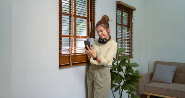 亚洲妇女用手机喝咖啡 通过无线通信进行视频通话 在家里玩得很开心 — 图库照片