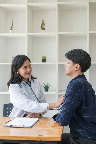 アジアの男性患者は彼の心拍数を聞くために女性医師を使用しながら彼の健康をチェックしています — ストック写真