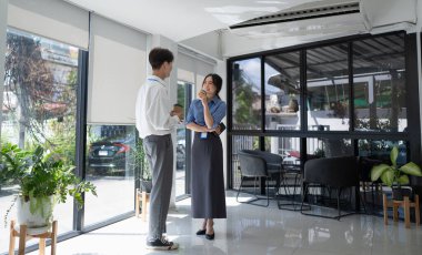 Kahve içerken ve ofiste sohbet ederken tabletle çalışan zeki bir işadamı..