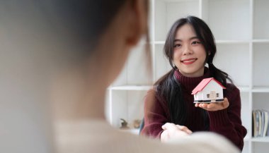 Emlakçılar ve müşteriler, arazisi olan bir ev alma sözleşmesi imzaladıkları için tebrik etmek için el sıkışıyorlar..