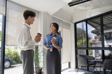 Kahve içerken ve ofiste sohbet ederken tabletle çalışan zeki bir işadamı..