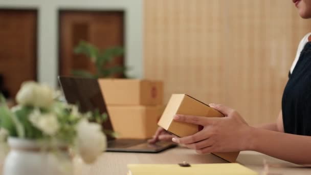 快乐的亚洲女企业主准备了包裹盒 检查网上的产品订单 然后用手提电脑发给顾客 网上购物概念 — 图库视频影像