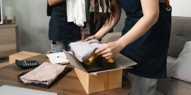 İki güzel bağımsız iş kadınının yakın plan görüntüsü çevrimiçi satılırken kendi küçük işletme E-ticaret nakliye konseptinde paket ürün kutusu hazırlıyor..
