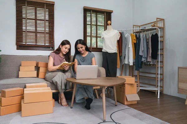 stock image Asian woman friends couple talk to sell the clothes at home. Young attractive business people female take a order clothing to customer in online retail to sales at living room.