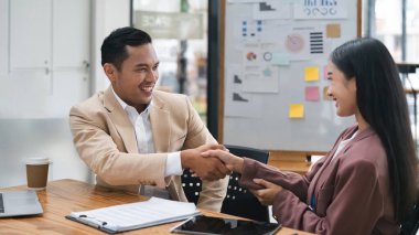 Genç Asyalı iş adamı el sıkışıyor. Anlaşma yapıyor, iş kadını tokalaşıyor..