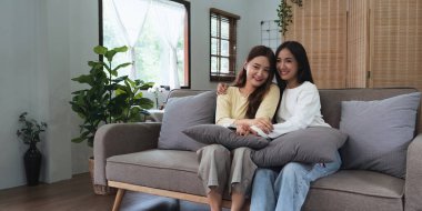 Asyalı genç kadın homoseksüel lezbiyen çift evlerinde sinema izlemek için kanepede oturdular..