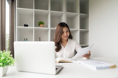 Ofisteki raporları incelerken bilgisayarını kullanan Asyalı iş kadını.