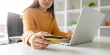 Yakın plan Asyalı kadın elinde kredi kartı ve akıllı telefon tutuyor, evinde oturuyor, mutlu genç bayan müşteri online alışveriş yapıyor..