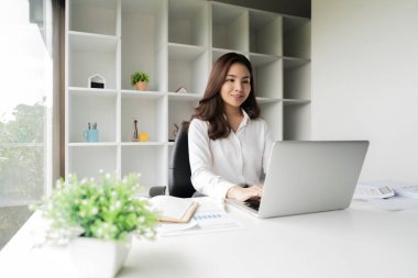 Ofisteki raporları incelerken bilgisayarını kullanan Asyalı iş kadını.