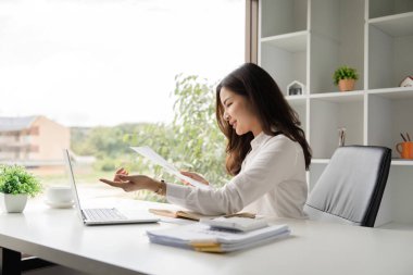 Ofisteki raporları incelerken bilgisayarını kullanan Asyalı iş kadını.