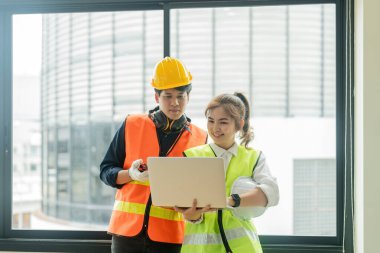 Mühendis ekibi, toplantı odasında inşaat sürecini tartışan yansıtıcı ceketler giyiyor..
