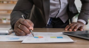 Veri analizi ve iş istatistikleri konsepti, laptopunu kullanan Afro-Amerikan işadamı iş analizi sonucu bilgi istatistikleri, grafik ve çizelgeler, rapor hazırlama veya stratejik planlama.