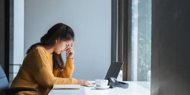 Genç iş kadını işiyle ve teslim tarihleriyle stresli iş kadını ofiste oturuyor..