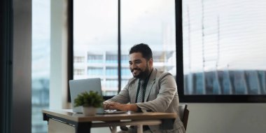 Hintli işadamı ofiste raporları incelerken dizüstü bilgisayar kullanıyor.