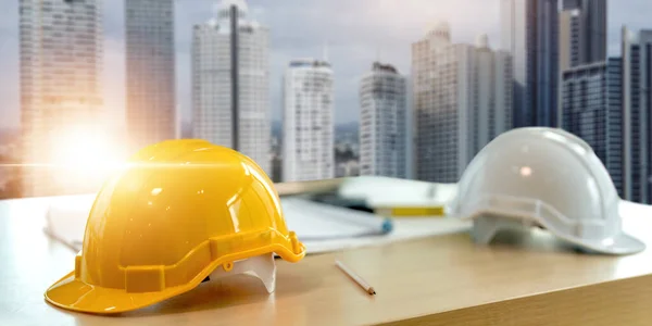 Yellow white safety helmet on workplace desk office center at construction site, contractor concept.