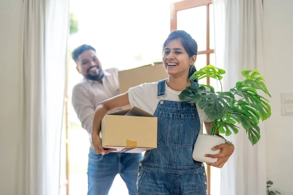Indian young couple move the box into the home at new home. Relocation, moving to new home concept.