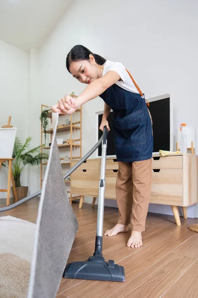 亚洲女人在家里客厅里打扫卫生 管家或女佣很乐意用吸尘器来清洁 — 图库照片