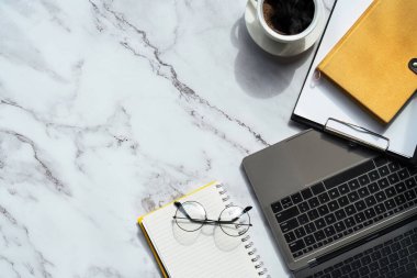 Üzerinde klavye bilgisayarı, not defteri ve kahve fincanı olan mermer desenli masa ve diğer ofis malzemeleri. İş ve finans kavramı. boş fotokopi alanı olan işyeri.
