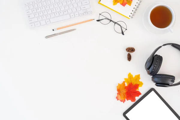 Top view above of desk workspace with blank copy space mockup, headphones, coffee cup, leaves on autumn background. top view work seasonal autumn concept.