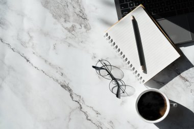 Üzerinde klavye bilgisayarı, not defteri ve kahve fincanı olan mermer desenli masa ve diğer ofis malzemeleri. İş ve finans kavramı. boş fotokopi alanı olan işyeri.